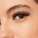 Close-up de um olho feminino com cílios alongados e curvados, mostrando o resultado de uma extensão profissional de cílios.